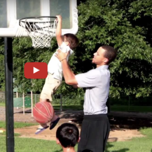 Father lifting his son to put the ball in the basket